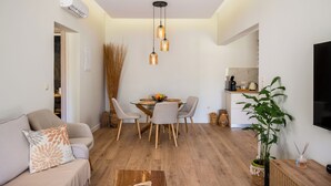 A modern living room with a dining table, chairs, a sofa, and a TV. - Phos Elegant Residences by Konnect, 400m to the beach - Two Bedroom Apartment (Corfu)