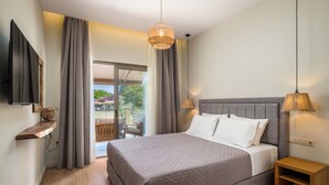 A bedroom with a large bed, a TV mounted on the wall, a wooden nightstand, and a view of the outdoors through a sliding glass door. - Phos Elegant Residences by Konnect, 400m to the beach - Two Bedroom Apartment (Corfu)