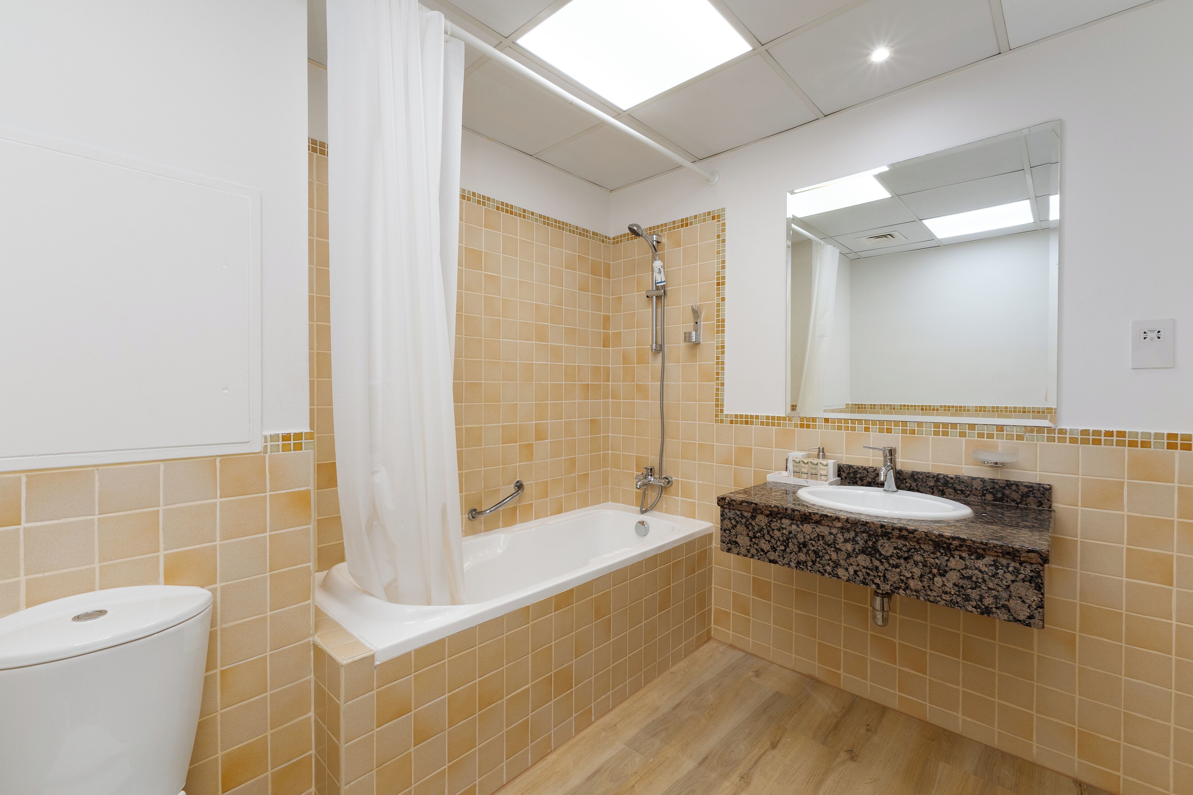 Une salle de bain avec une baignoire, des toilettes et un lavabo avec un miroir au-dessus.