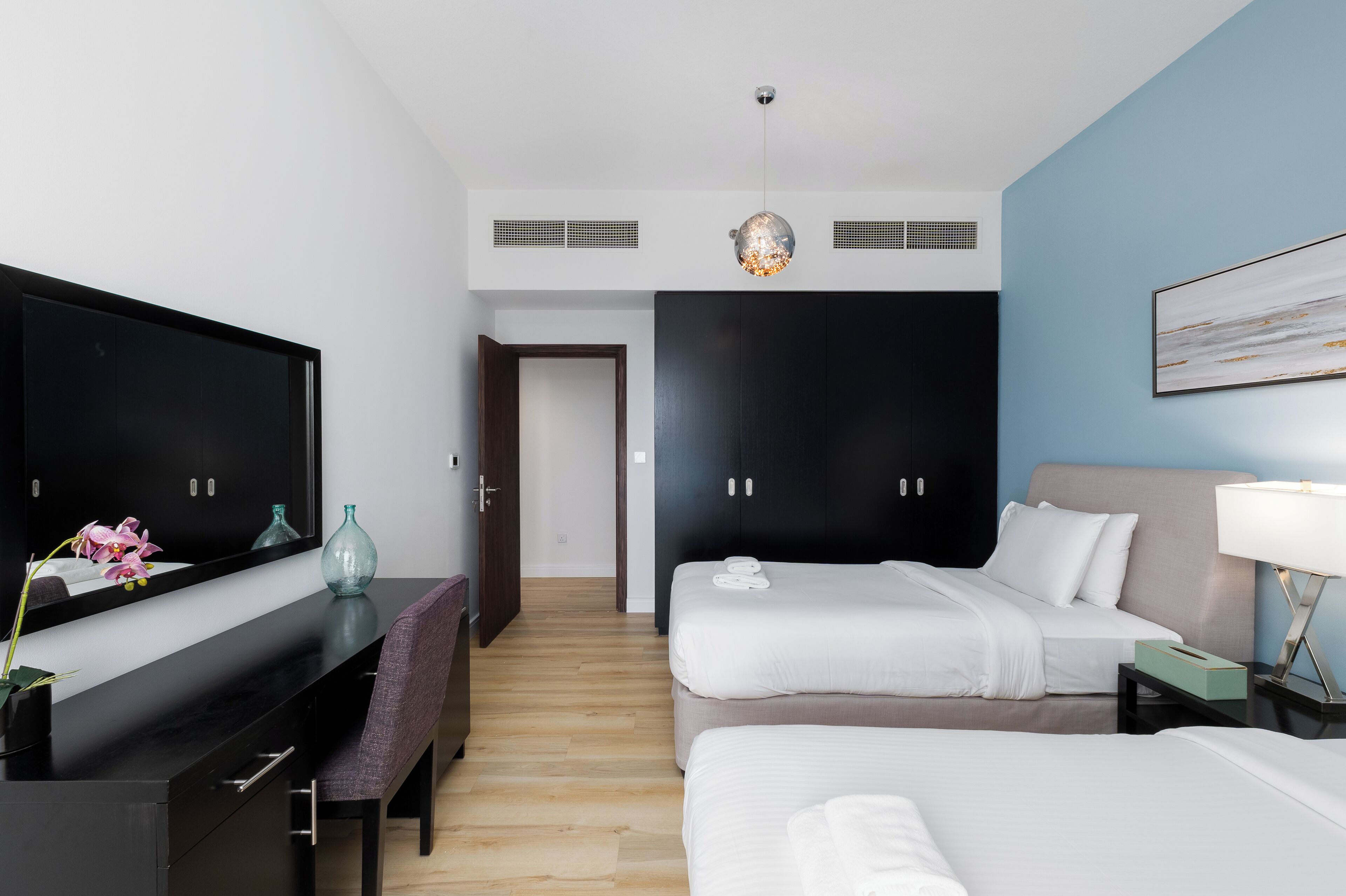 A hotel room with a bed, bedside table, lamp, and a TV on a stand.