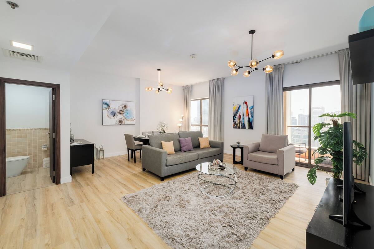 Ein modernes Wohnzimmer mit grauem Sofa, einem Couchtisch und einem Fernseher auf einem Schrank.