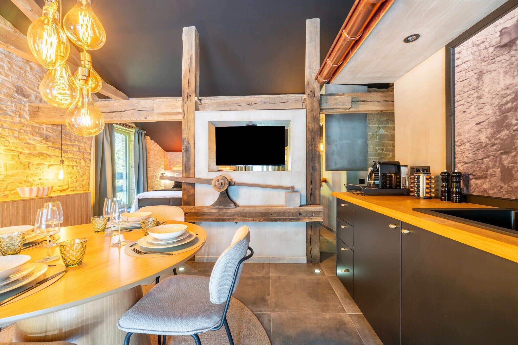 A modern kitchen with a wooden ceiling, a built-in oven, and a dining area with a table set for two.