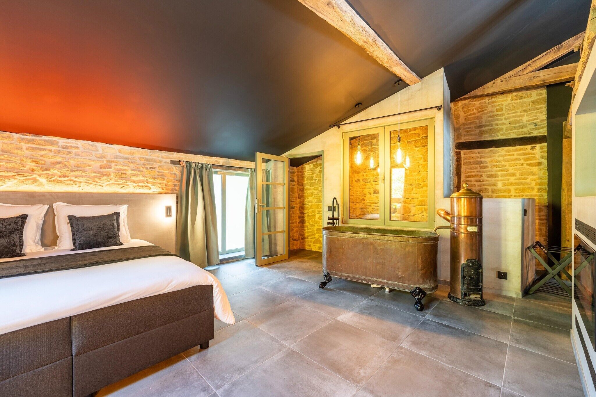Un dormitorio con cama, un baño con bañera y una pared de piedra.