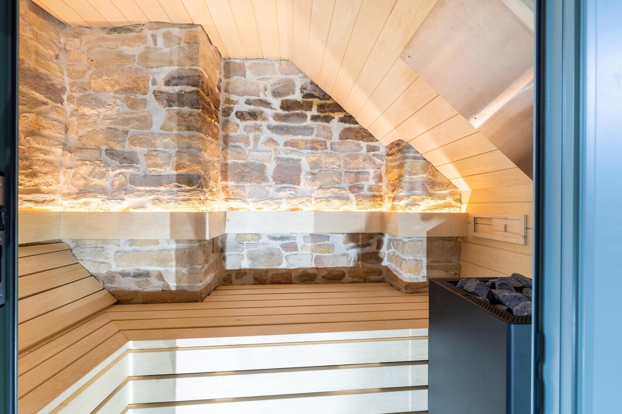 Une cheminée en pierre avec un banc en bois, un mur en pierre et un plafond en pente.