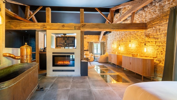 Une pièce spacieuse avec un mur en pierre, une cheminée et des poutres en bois.