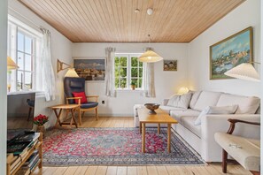 Ein gemütliches Wohnzimmer mit Holzboden, einer Couch, einem Tisch und einem Sessel.