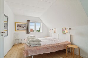 Ein Schlafzimmer mit einem Bett, einem Sessel, einem Fenster und einer Heizung.