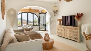 Amplia sala de estar con un ventanal grande, un sofá, un televisor y un aparador decorativo.