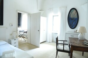 Una habitación de hotel con cama, escritorio, silla, mesa y un cuadro en la pared.