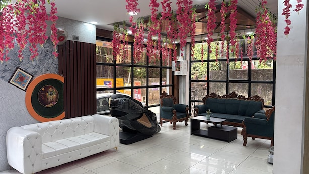 A modern interior with a white sofa, a dark armchair, and a green sofa set. - Hotel Bless Inn (Patna)