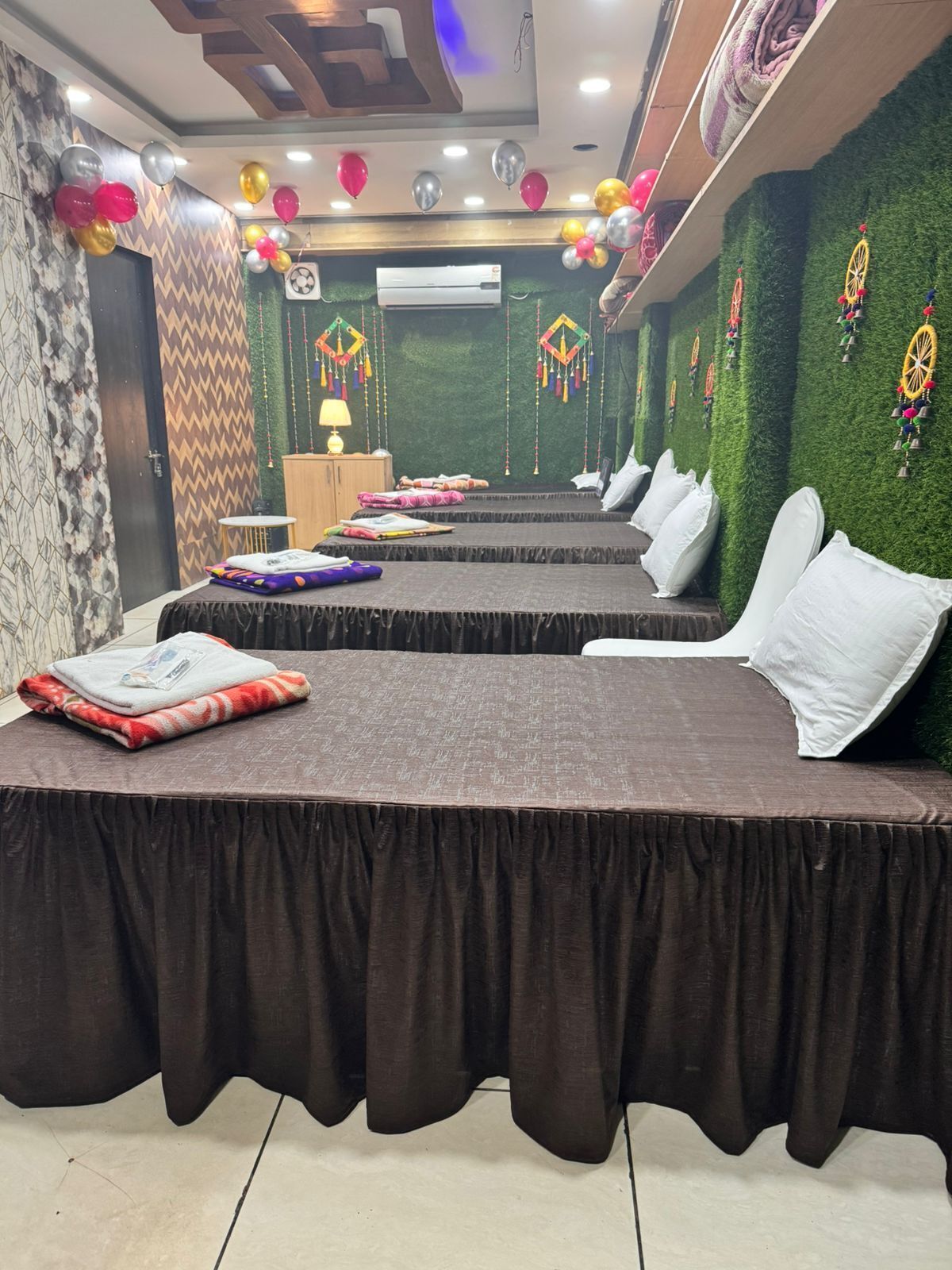 A room with two beds, a small table, and a wall decorated with balloons and hanging ornaments.
