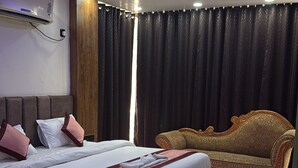 A modern bedroom with a bed, a sofa, and a ceiling light fixture. - Hotel Bless Inn (Patna)