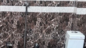 A toilet in a bathroom with a marble floor and walls.