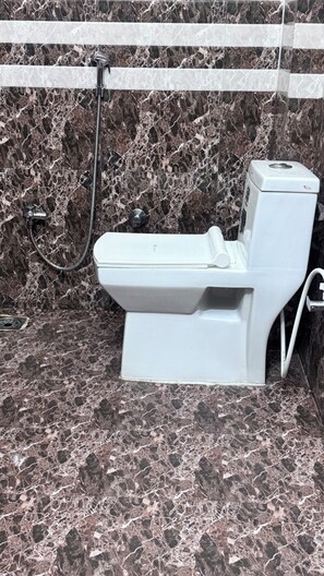 A toilet in a bathroom with a marble floor and walls.