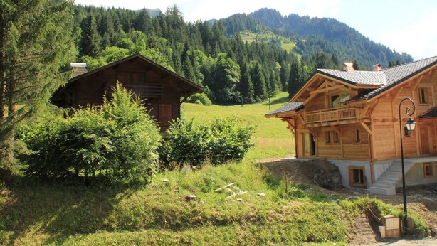 A wooden cabin with a balcony, surrounded by lush greenery and mountains in the background. - Holiday home in Chatel near ski area (Châtel)