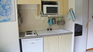 A compact kitchen with a built-in stove, a small sink, and a microwave. - Holiday home in Chatel near ski area (Châtel)