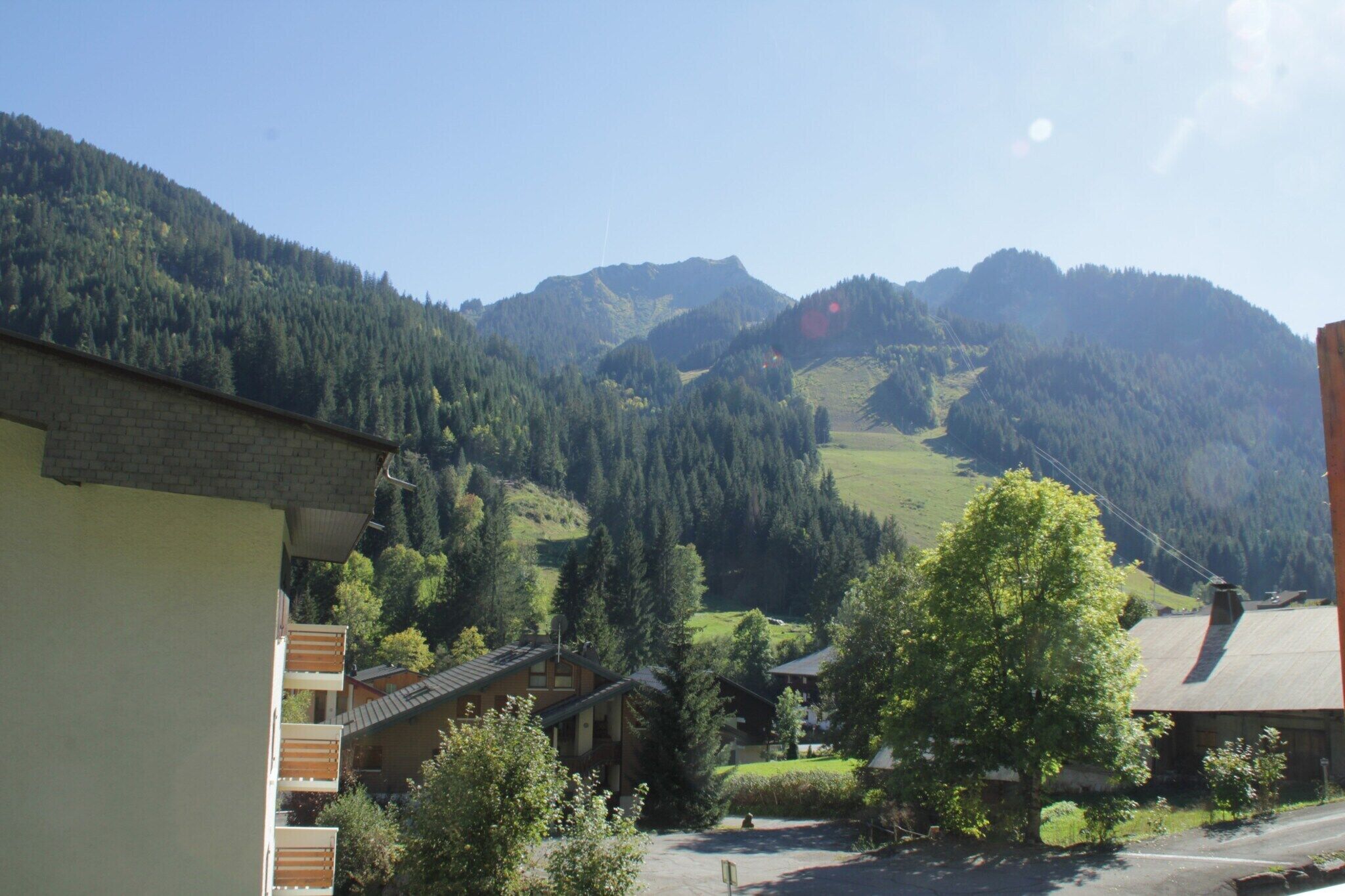 A mountain village with traditional buildings, a clear sky, and a valley.