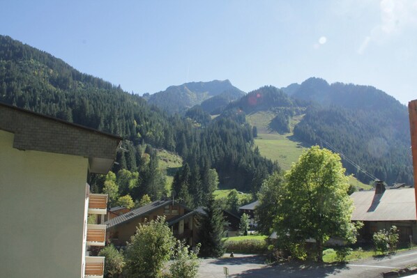 A mountain village with traditional buildings, a clear sky, and a valley.