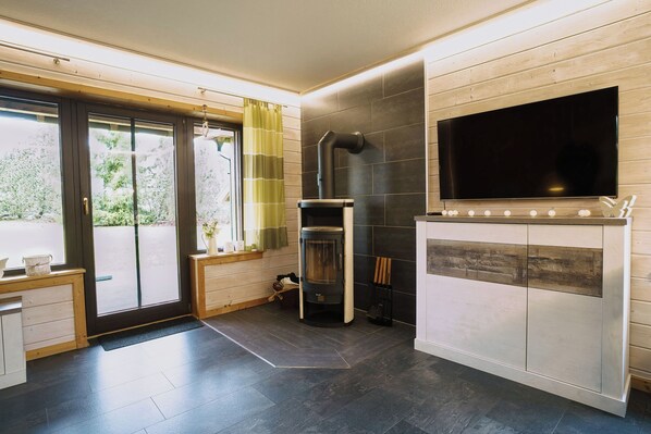 A modern kitchen with a built-in fireplace, a large flat-screen TV, and a sliding glass door leading to a balcony.