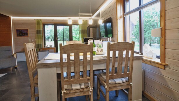 A wooden interior with a dining table, chairs, and a large window. - Your Holiday Home With Fireplace in the Harz (Oberharz am Brocken)