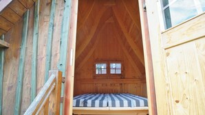A wooden attic bedroom with a bed, a window, and a door. - Your Holiday Home With Fireplace in the Harz (Oberharz am Brocken)