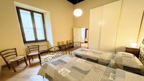 A bedroom with two beds, a window, a chair, and a bedside table with a lamp. - 6 Guests apt With Terrace in Pedestrian Historic Centre of Spoleto (Spoleto)
