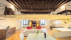 Un'ampia zona giorno con cucina moderna, un tavolo da pranzo con bottiglia e bicchieri, e un caminetto.