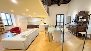 Un espacio habitable amplio con un sofá, una mesa de comedor y sillas. Se observa una cocina al fondo, con electrodomésticos modernos.