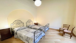 Un dormitorio con dos camas, una silla de madera y una mesita de noche.