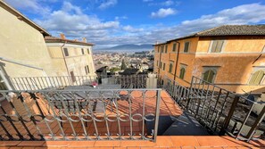 Una terraza en la azotea con barandillas metálicas, una mesa y sillas.