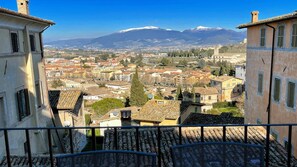 Un balcón con vistas a un pueblo de edificios tradicionales y una montaña al fondo.