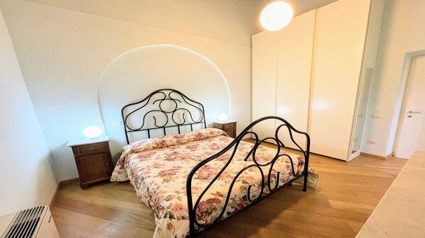 Une chambre à coucher avec un lit, une table de chevet, une lampe fixée au mur et une porte.