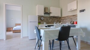A modern kitchen with white cabinets, a built-in oven, and a dining area with a table set for two. - VillaRealeFlats (Lecce)