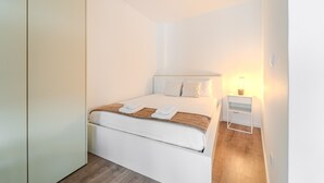 A modern bedroom with a bed, bedside table, and a nightstand with a lamp. - LZ Studio by House and People (Braga)