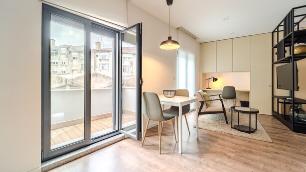 A modern living room with a dining area, large sliding glass doors to a balcony, and a black TV stand. - LZ Studio by House and People (Braga)
