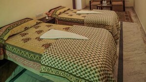 Ein Hotelzimmer mit zwei Betten, einem Deckenventilator und einer kleinen Sitzecke.