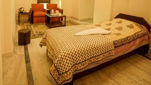 Ein Schlafzimmer mit einem großen Bett, einem Sessel, einem kleinen Tisch und einem Deckenventilator.