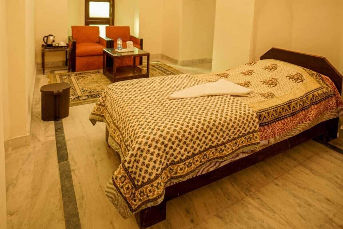 A bedroom with a large bed, a chair, a small table, and a ceiling fan.