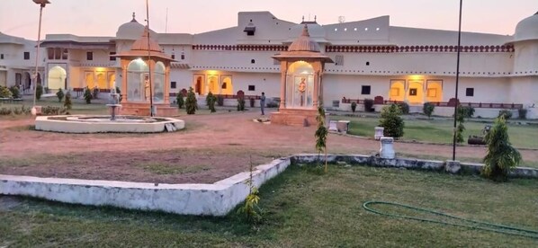 A courtyard with a fountain, two lamp posts, and a building with multiple doors and windows. - Bhadrawati Palace (Dausa)