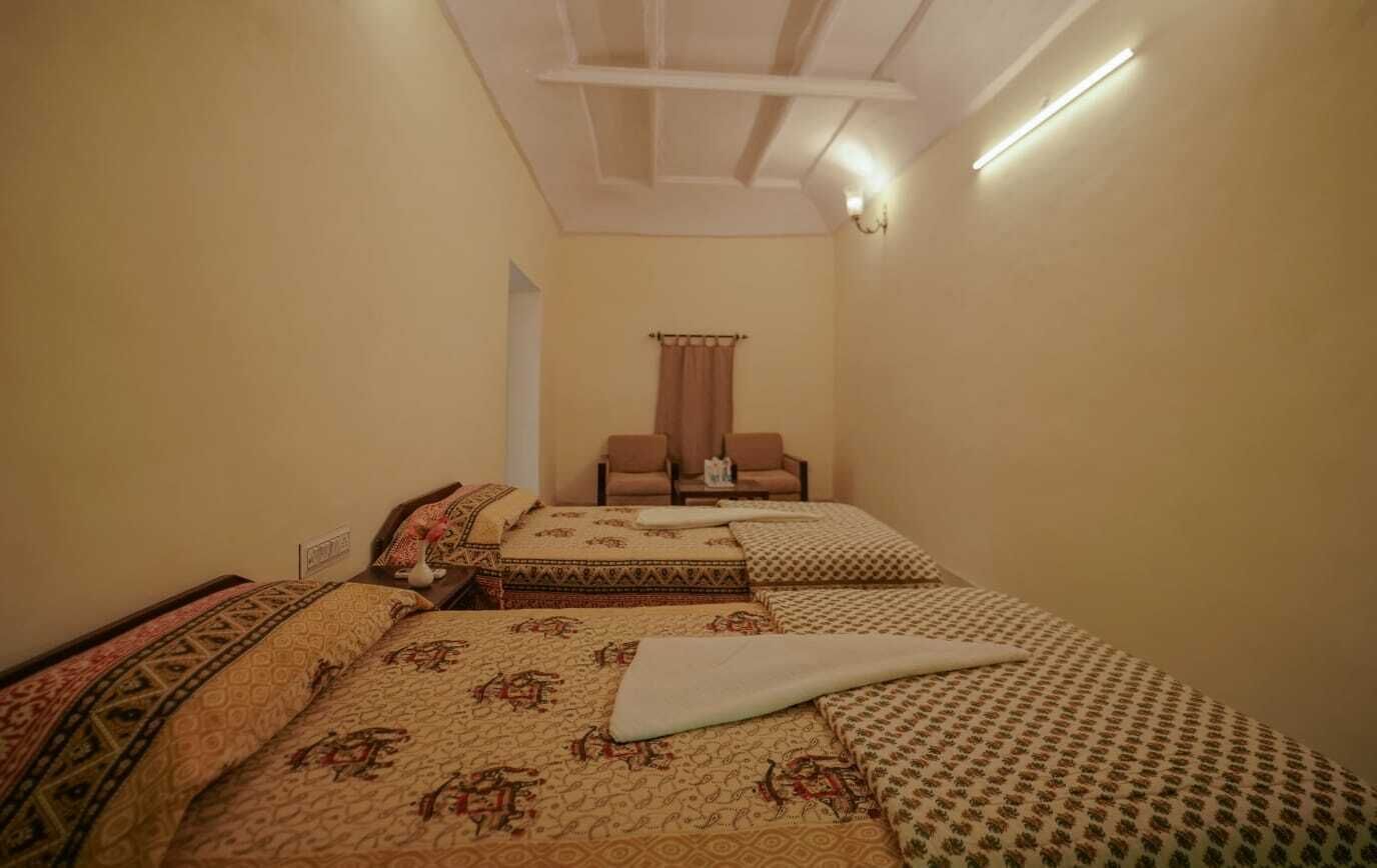 Een hotelkamer met twee bedden, een zithoek met een fauteuil en een plafondlamp.