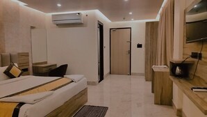 A modern hotel room with a bed, bedside table, TV, and a wooden bench. - The park green hotel & resort (Chandauli)