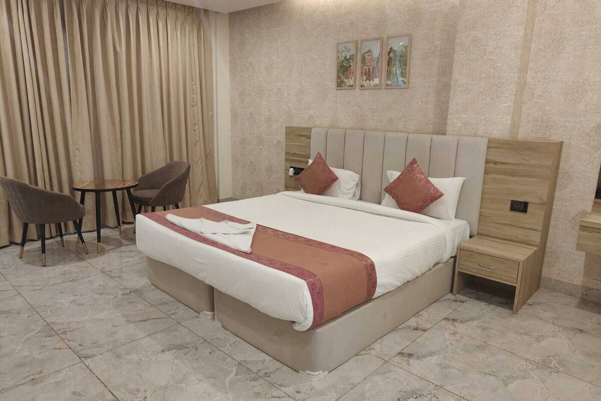 A hotel room with a large bed, two bedside tables, a chair, and a small table.