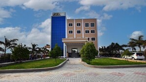 A hotel with a prominent blue and beige facade, a central entrance, and a paved walkway leading to the entrance. - The park green hotel & resort (Chandauli)