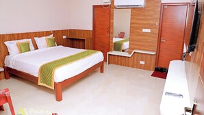 A hotel room with a wooden bed, a mirror, an air conditioning unit, and a TV. - AA Residency (Tirupati)