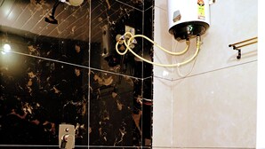 A bathroom with a toilet, a shower, and a water heater. - AA Residency (Tirupati)