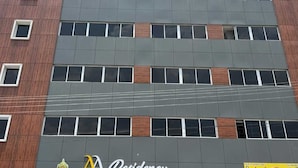 A multi-story building with a modern facade, featuring a combination of brick and grey panels, and several windows. - AA Residency (Tirupati)