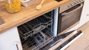 Une cuisine avec un plan de travail en bois, un lave-vaisselle ouvert et une cuisinière.