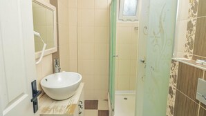 A bathroom with a white sink, a mirror, a shower enclosure, and a toilet. - Gerence Alacati  (Cesme)