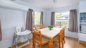 A dining area with a wooden table, six chairs, a high chair, and a small potted plant.