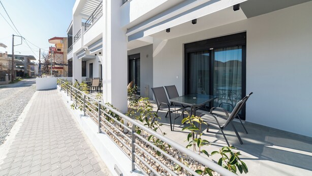 A modern building with a balcony, outdoor seating, and a paved walkway.